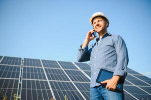 a retrato do uma jovem engenheiro Verificações com tábua Operação com sol, limpeza em campo do fotovoltaico solar painéis. conceito renovável energia, tecnologia, eletricidade, serviço, verde poder foto