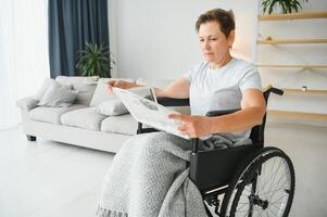 mulher dentro cadeira de rodas lendo jornal dentro de casa foto