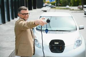 uma homem de negocios cobranças a elétrico carro foto