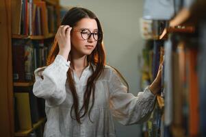 dentro a biblioteca - bonita fêmea aluna com livros trabalhando dentro uma Alto escola biblioteca. foto