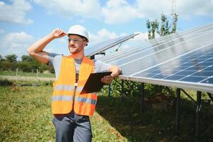 masculino trabalhador com solar baterias. homem dentro uma protetora capacete. instalando estar sozinho solar painel sistema foto