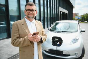 uma homem de negocios cobranças a elétrico carro foto