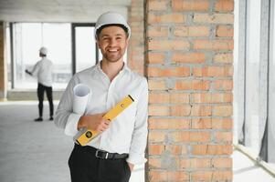 retrato do a arquiteto construtor estudando disposição plano do a quartos, sério Civil engenheiro trabalhando com documentos em construção site, construção e casa renovação, profissional capataz às trabalhar. foto