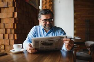 café pausa. homem bebendo café e lendo jornal dentro cafeteria Barra foto
