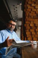 café pausa. homem bebendo café e lendo jornal dentro cafeteria Barra foto