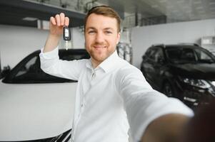 jovem homem é escolhendo uma Novo veículo dentro carro concessionária e fazer foto em uma Smartphone.