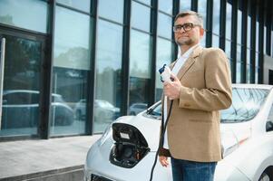 homem segurando poder conector para elétrico carro foto