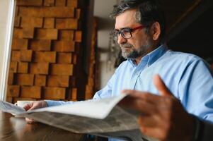 jornal dentro a manhã. Senior homem de negocios às dele escritório equitação jornais. foto