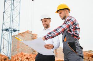 engenheiro arquiteto com Difícil chapéu e segurança colete trabalhando juntos dentro equipe em principal construção local foto