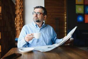 café pausa. homem bebendo café e lendo jornal dentro cafeteria Barra foto