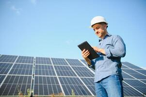 a retrato do uma jovem engenheiro Verificações com tábua Operação com sol, limpeza em campo do fotovoltaico solar painéis. conceito renovável energia, tecnologia, eletricidade, serviço, verde poder foto