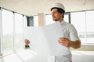 retrato do a arquiteto construtor estudando disposição plano do a quartos, sério Civil engenheiro trabalhando com documentos em construção site, construção e casa renovação, profissional capataz às trabalhar. foto