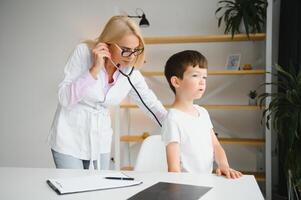 pediatra médico examinando pequeno Rapazes coração batida e pulmões para Verifica para problemas foto