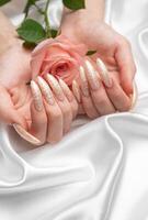 fêmea mãos em uma branco seda fundo com lindo pérola manicure foto