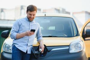 sorridente homem desconectando a carregador a partir de a carro foto