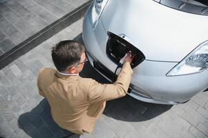 homem segurando poder conector para elétrico carro foto