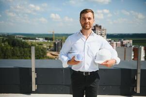 o negócio arquiteto homem vestindo capacete de segurança em pé do uma construção projeto foto