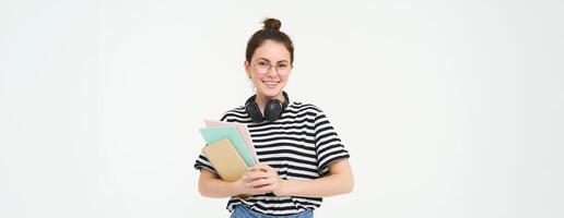 imagem do jovem mulher, tutor com livros e cadernos, vestindo fones de ouvido sobre dela pescoço, isolado em branco fundo. aluna estilo de vida conceito foto