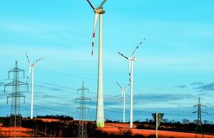 vento Fazenda parque e Alto Voltagem torres Próximo para uma estrada dentro Áustria dentro ensolarado clima. foto