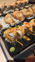 fechar acima do Sushi dentro Preto plástico caixa, japonês Comida. Sushi rolos com salmão e camarão foto