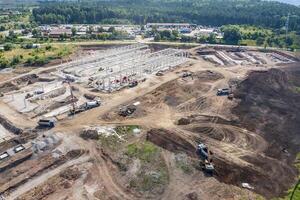 aéreo topo Visão do enorme construção local com muitos trabalhando pesado máquinas foto