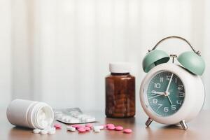 cuidados de saúde Essenciais com a alarme relógio, pílulas, e remédio garrafa em uma branco cortina fundo foto