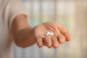 mulher mão segurando pílulas em borrado fundo foto