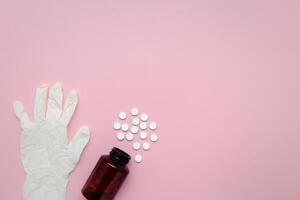 uma garrafa do medicamento, pílulas, e látex luvas em uma Rosa fundo foto