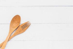 de madeira cozinha utensílios Incluindo uma colher e garfo em branco mesa fundo foto