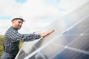 especialista é inspecionando qualidade do uma solar baterias. trabalhador dentro uniforme e capacete com equipamento. ecologia poder conservação conceito. foto