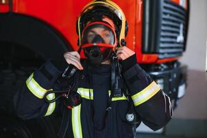foto do bombeiro com gás mascarar e capacete perto fogo motor