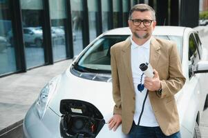 homem segurando poder conector para elétrico carro foto