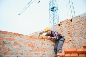 amarelo colori Difícil chapéu. jovem homem trabalhando dentro uniforme às construção às dia. foto
