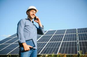 a retrato do uma jovem engenheiro Verificações com tábua Operação com sol, limpeza em campo do fotovoltaico solar painéis. conceito renovável energia, tecnologia, eletricidade, serviço, verde poder foto