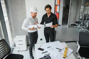 engenheiro ou arquiteto trabalho em equipe trabalhando em construção projeto com construção modelo e projeto dentro escritório. construção conceito. foto