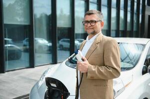 homem segurando poder conector para elétrico carro foto