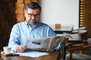 café pausa. homem bebendo café e lendo jornal dentro cafeteria Barra foto