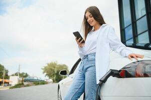 elétrico carro cobrando dentro rua. ecológico carro conectado e cobrando baterias. menina esperando poder fornecem conectar para elétrico veículos para carregando. foto