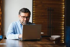 negócios, tecnologia e pessoas conceito , Senior homem de negocios com computador portátil computador bebendo café às moderno cafeteria. foto