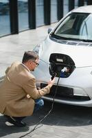 homem segurando poder conector para elétrico carro foto