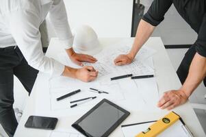 engenheiro ou arquiteto trabalho em equipe trabalhando em construção projeto com construção modelo e projeto dentro escritório. construção conceito. foto