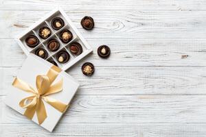 branco caixa com chocolates doces e dourado fita. topo Visão com cópia de espaço foto