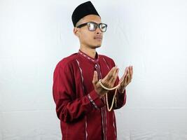 religioso ásia muçulmano homem dentro tradicional vestir usando oração miçangas isolado em branco fundo foto
