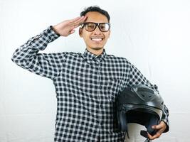 retrato ásia homem segurando motocicleta capacete com animado expressão. segurança cavalgando. foto