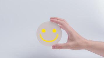 cliente serviço avaliação e satisfação pesquisa conceitos. a do cliente mão segurando a feliz face sorrir face ícone em círculo madeira foto