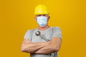 retrato do uma trabalhador com capacete e protetora mascarar para cobiçado isolado em amarelo fundo foto