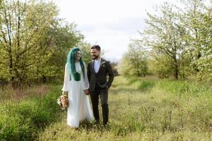 uma barbudo noivo e uma menina com verde cabelo estão caminhando foto