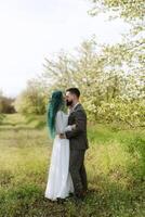 uma barbudo noivo e uma menina com verde cabelo estão caminhando foto