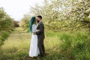 uma barbudo noivo e uma menina com verde cabelo estão caminhando foto