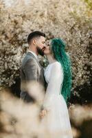 uma barbudo noivo tocam e uma menina com verde cabelo contra a fundo do florescendo Primavera foto